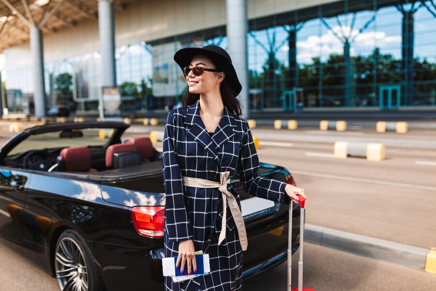 beautiful-smiling-girl-sunglasses-black-hat-holding-passport-with-flight-ticket-joyfully-looking-aside-near-airport-with-cabriolet-car-background_574295-695
