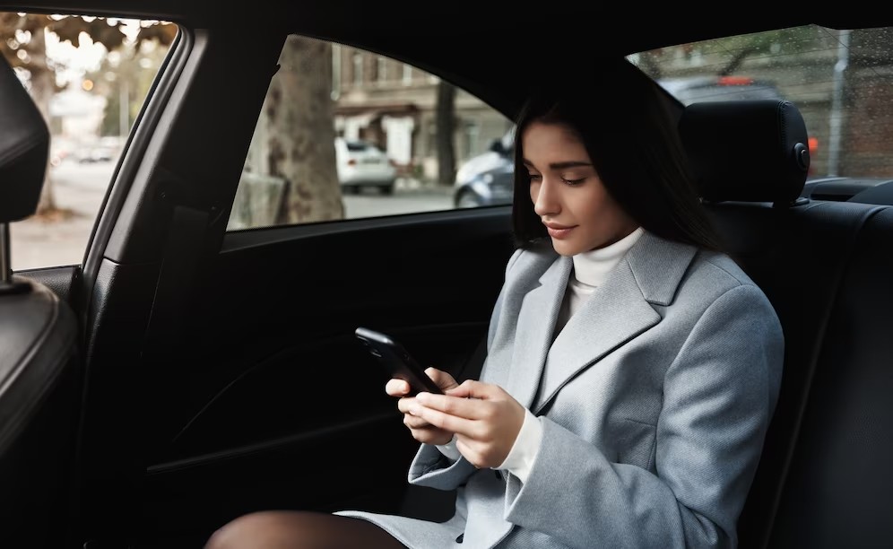 businesswoman-travelling-by-car-backseat-reading-text-message-smartphone-while-driving-meeting_197531-22616